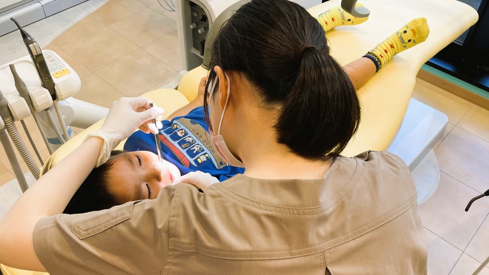 小児専用の診療台で、歯科衛生士がお子様の歯を診ているところ